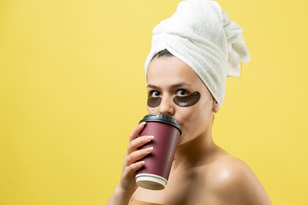 Young beautiful girl in a white towel on his head wears collagen gel patches under her eyes