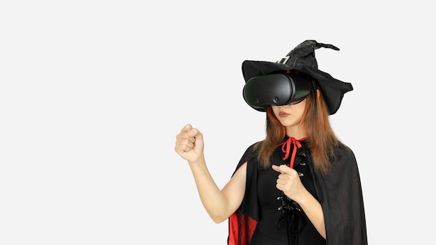 A Young beautiful girl with black and orange hair in black dress and witch hat is boxing the air during the VR experienceisolated on white background