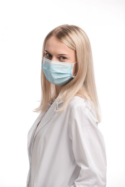 Young beautiful girl with blond hair in a medical mask on white background