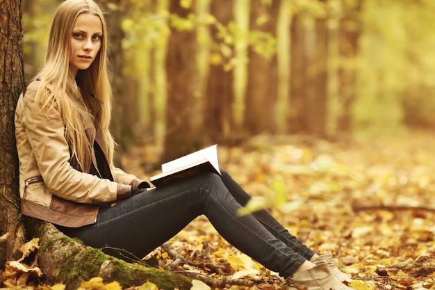 young beautiful girl with a book in the autumn forest