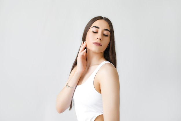 Young beautiful girl with clean skin Women without wrinkles on the face closeup on a gray background