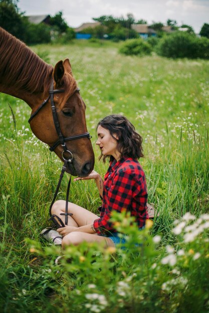 Photo a young beautiful girl with dark hair spends time with her horse