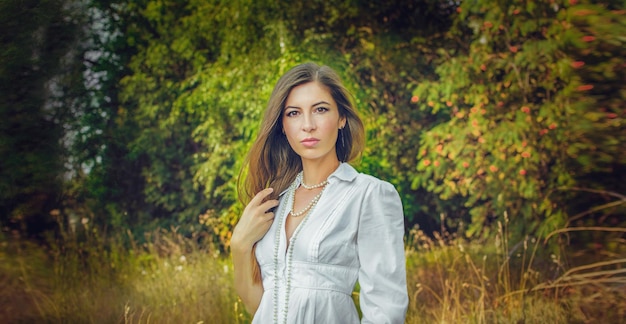 A young beautiful girl with flowers poses in the spring in the park