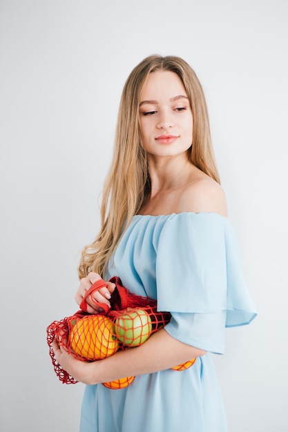 Young beautiful girl with fresh fruit in a string bag. The concept of zero waste. Toning.