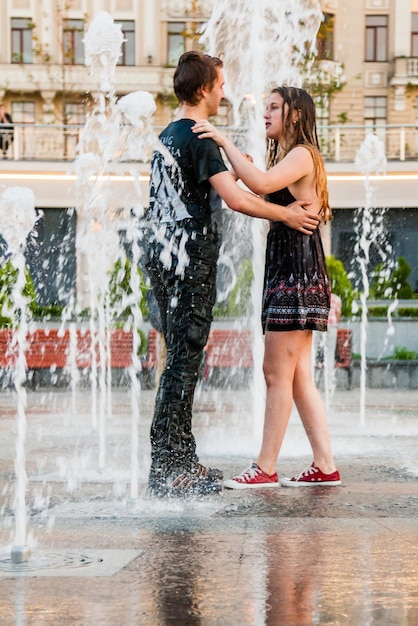 Young beautiful girl with a guy dancing in a fountain