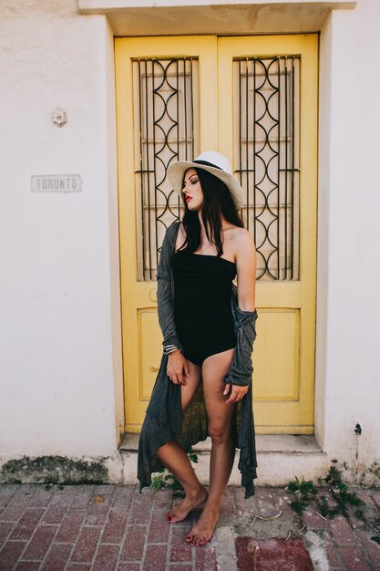 young beautiful girl with  hat posing against the backdrop of a vintage door