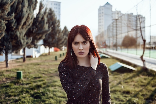 Young beautiful girl with heavy and sullen look in black dress outside posing during sunset