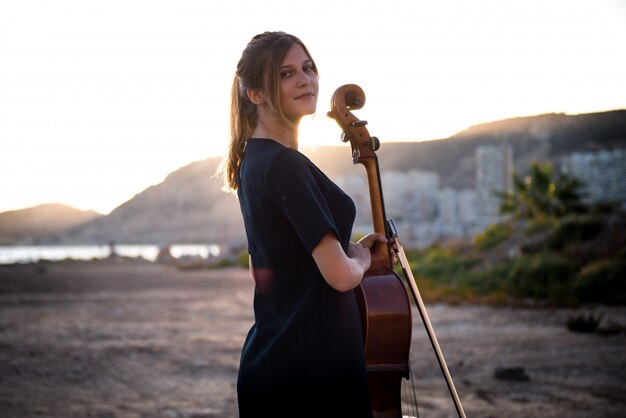 Young beautiful girl with her cello on the outside