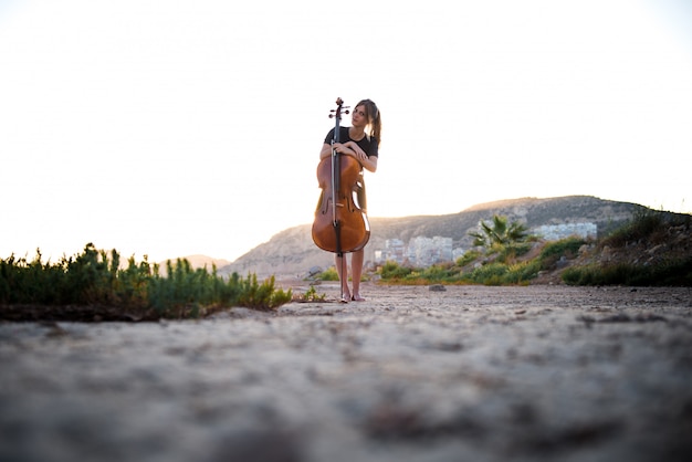 Young beautiful girl with her cello on the outside