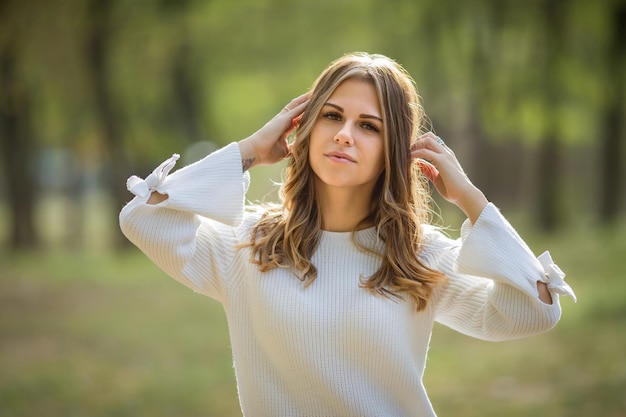 A young beautiful girl with her hands up smiling in an autumn park High quality photo