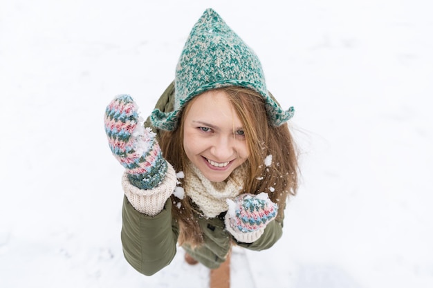 長いブロンドの髪を持つ若い美しい少女は、最初の雪を楽しんでいます