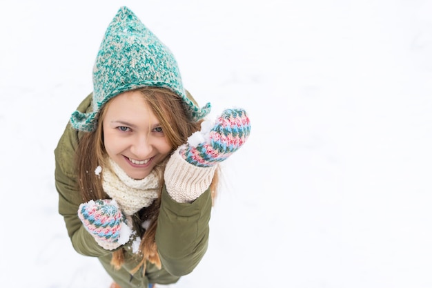 長いブロンドの髪を持つ若い美しい少女は、最初の雪を楽しんでいます