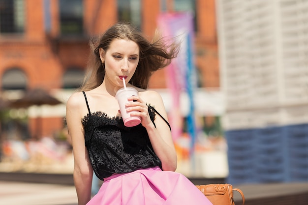 Young beautiful girl with long hair drinks fruit smoothie.