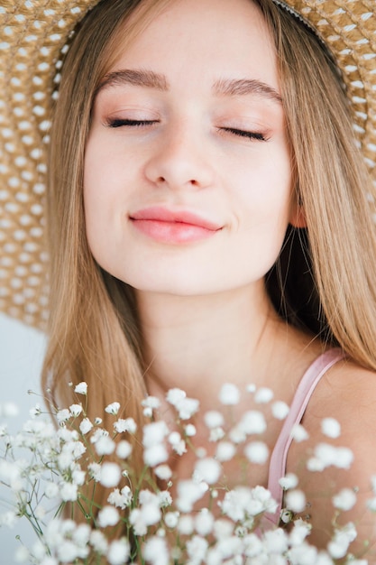 白い花の花束でポーズをとって長い髪と帽子を持つ若い美しい少女。調色。