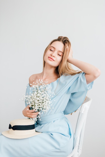 Young beautiful girl with long hair and hat posing with a bouquet of white flowers. Toning.