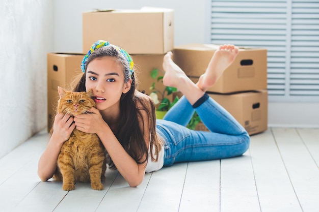 Young beautiful girl with red cat, and with boxes for the move