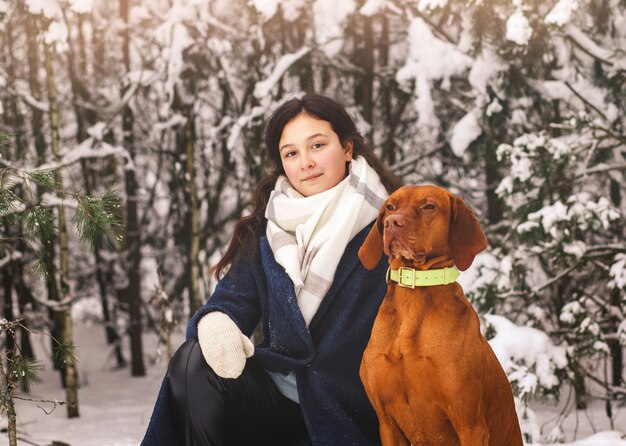 Young beautiful girl with red dog in winter in nature