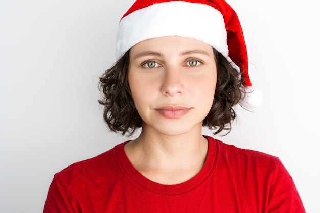 산타 모자와 흰색 배경에 고립 된 빨간 옷과 같은 산타 클로스 액세서리와 함께 젊은 아름 다운 소녀. 크리스마스 사진입니다. 브라질 사람, 백인, 검은 머리, 녹색 눈.