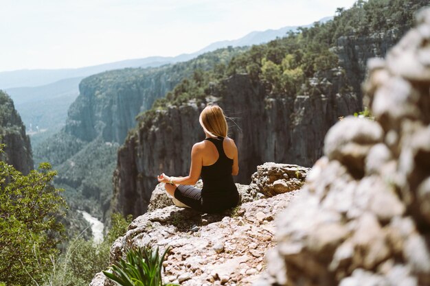 Foto giovanetta bellissima donna in abito nero sportivo sottile che medita sul picco della scogliera di edge rock mountain