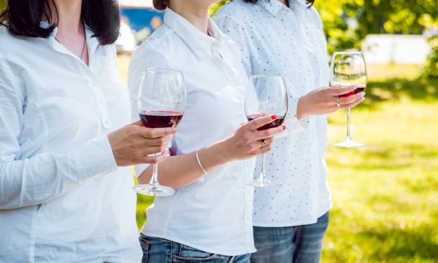 Young beautiful girls with glass of red wine in the park