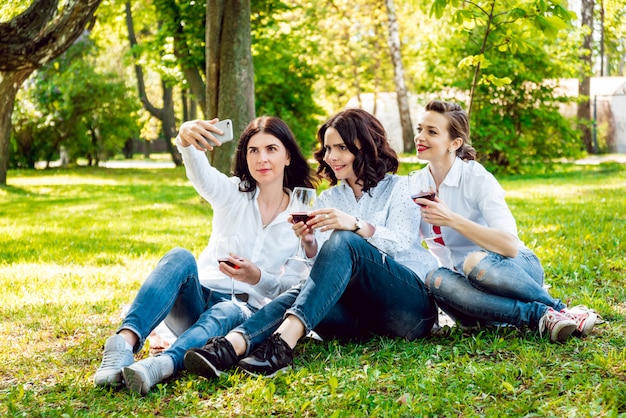 Young beautiful girls with glass of red wine in the park