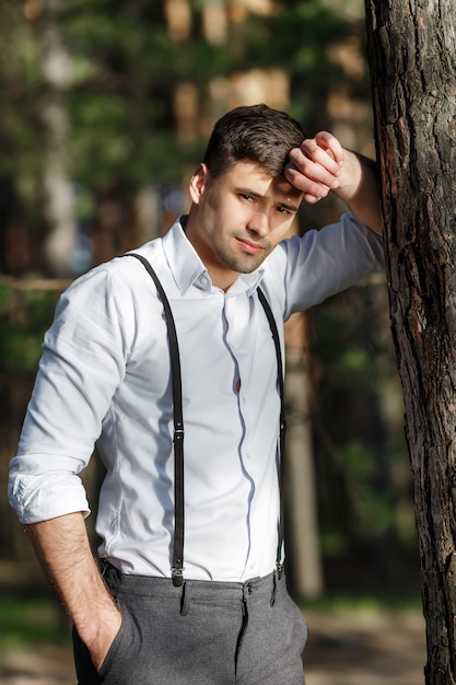 Young beautiful groom against a tree