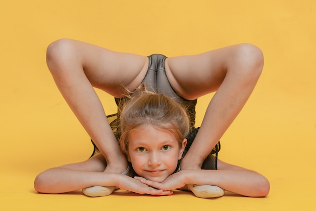 Молодая красивая гимнастка в спортивной одежде выполняет элемент гимнастики тренировки стойки на руках