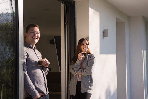 young beautiful handsome couple enjoying morning coffee on the door of their luxury home villa