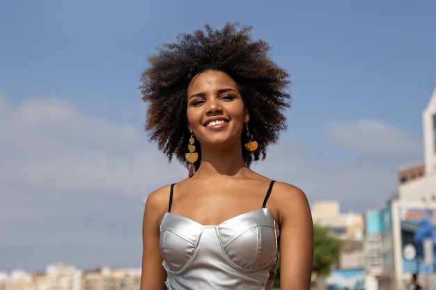 Young beautiful happy African woman walking with blue sky background