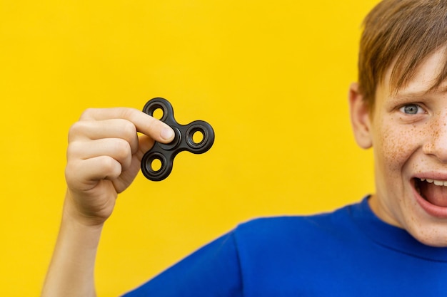 Young beautiful happy boy with freckles blue tshirt holding fidget spinner