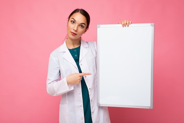 Young of beautiful happy brunet woman wearing medical white coat holding white magnetic board for