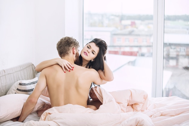 Photo young beautiful and happy couple man and woman at home in bedroom in bed loving and sexy