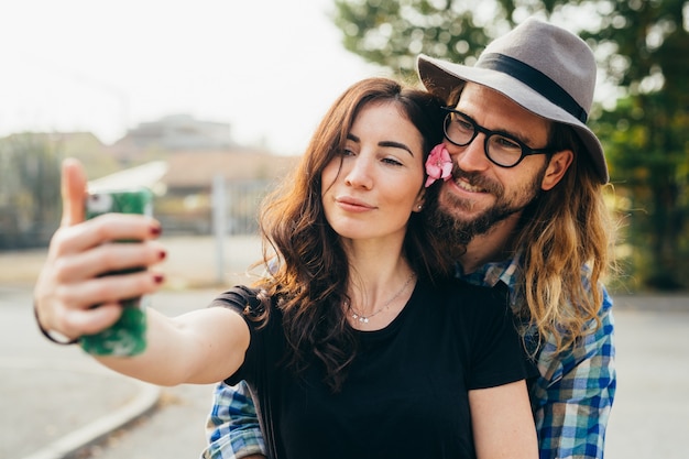 Photo young beautiful happy couple walking outdoor taking selfie using smartphone