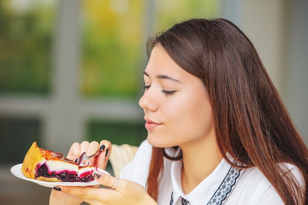 Giovane bella ragazza felice che gode della fine della torta di formaggio dolce fresca deliziosa su