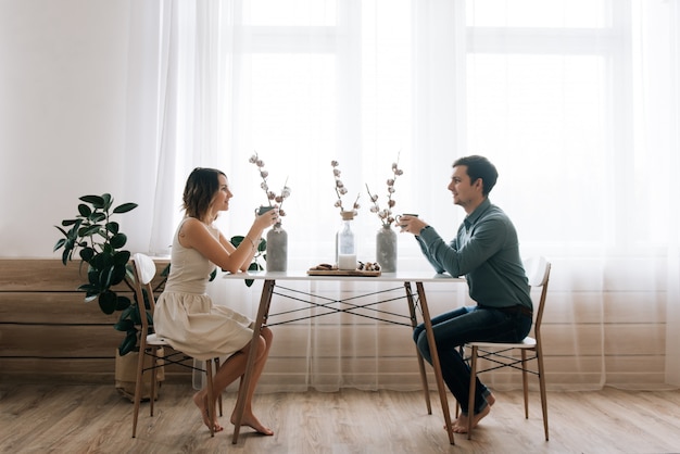 Young beautiful happy loving couple sitting at the table looking at each other