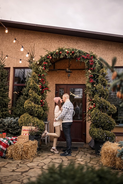 Young beautiful happy smiling couple standing near decorated house for Christmas Christmas New Year winter holidays