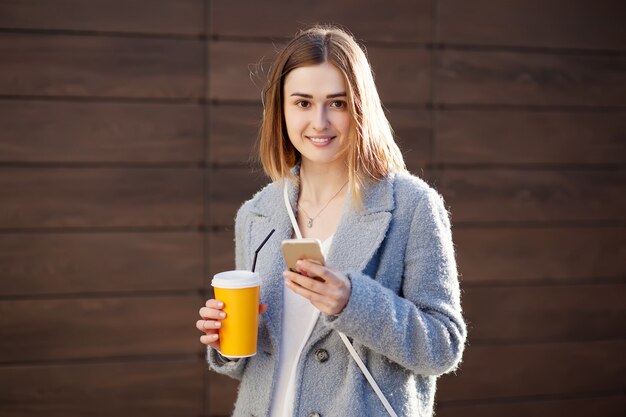 カクテル、滑らかな飲み物を持つ若い美しい幸せなスタイリッシュな内気な少女