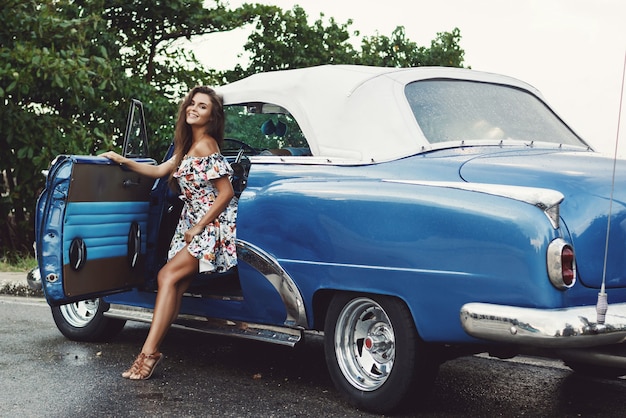 Photo young, beautiful and happy woman driving a retro convertible car