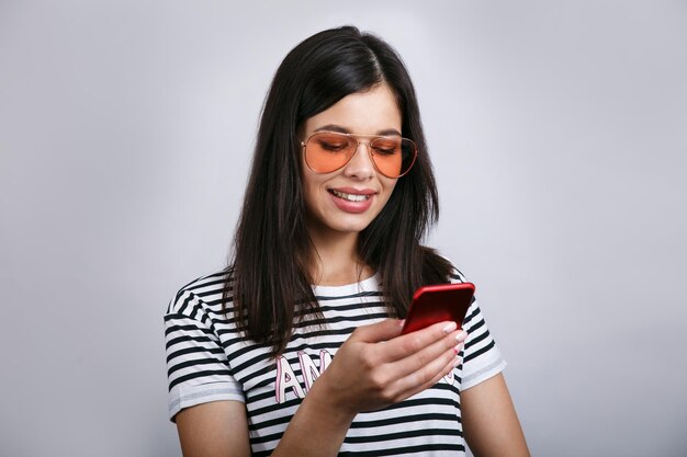 Young beautiful happy woman using smart phone Isolated on grey background