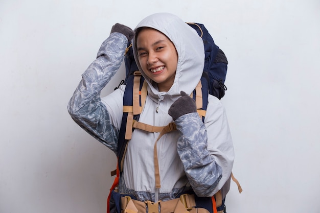 배낭을 메고 흰 배경에 격리된 강한 몸짓을 하는 젊은 아름다운 등산객 아시아 여성