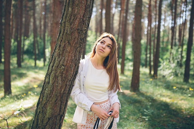 Young beautiful hippie woman walks in the summer forest laughs dances and enjoys life and nature