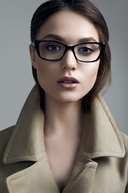 Фото Молодая красивая хипстерская женщина в модном пальто и очках