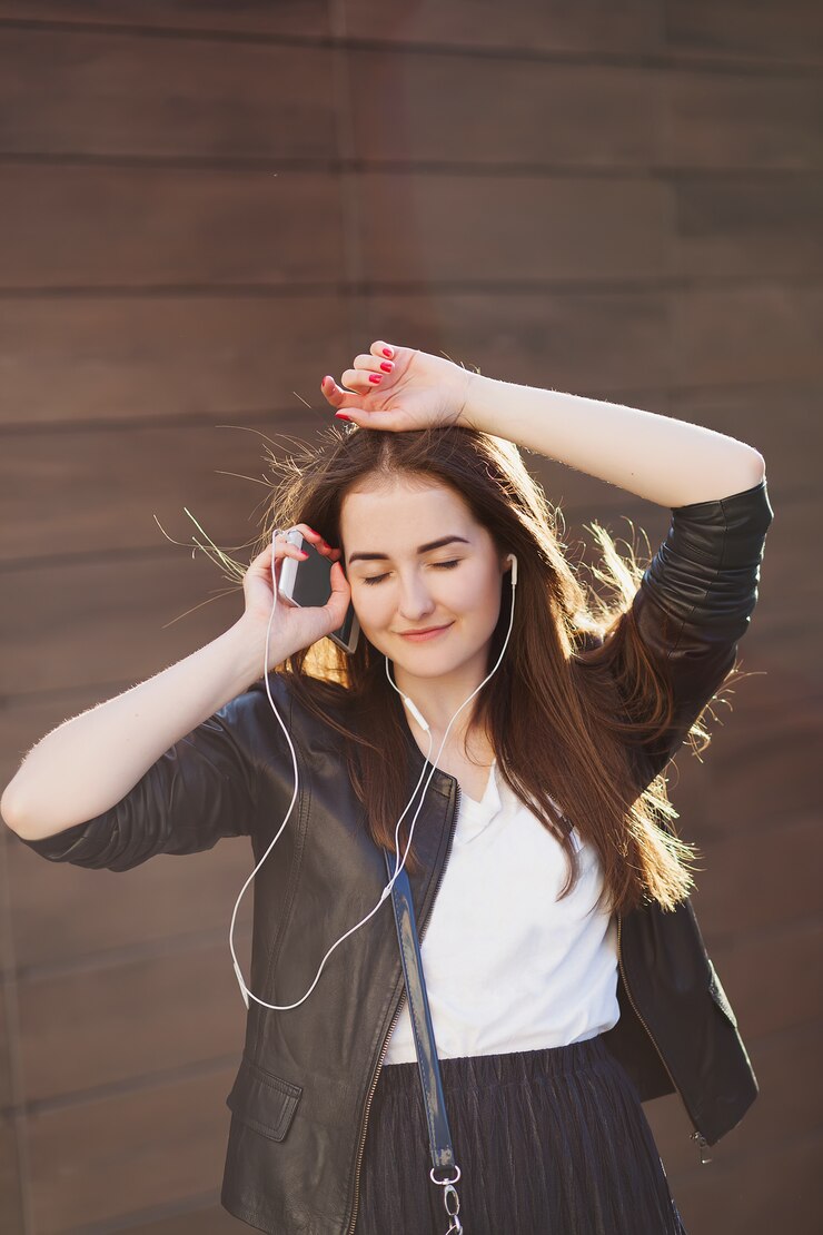 市内のヘッドフォンで音楽を聴く若い美しい流行に敏感な女性。