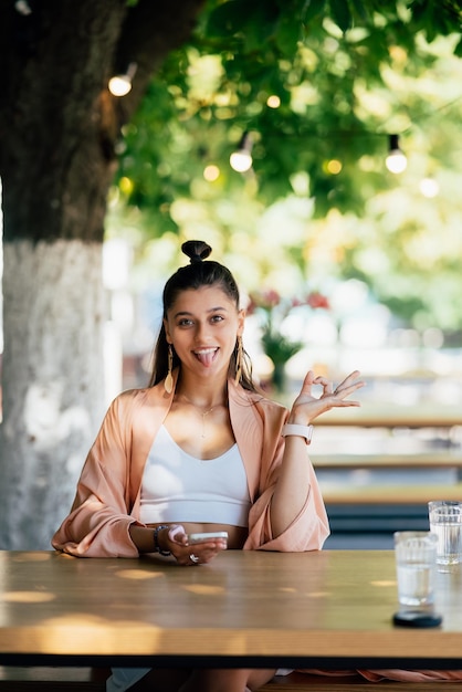 Young beautiful hipster woman sitting in veranda cafe in street