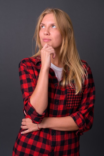  young beautiful hipster woman with blond hair against gray wall