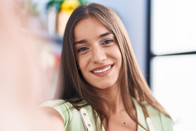 Young beautiful hispanic woman florist smiling confident make selfie by camera at flower shop