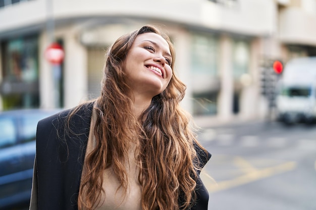 若い美しいヒスパニック系女性が自信を持って笑顔で通りを横に見て