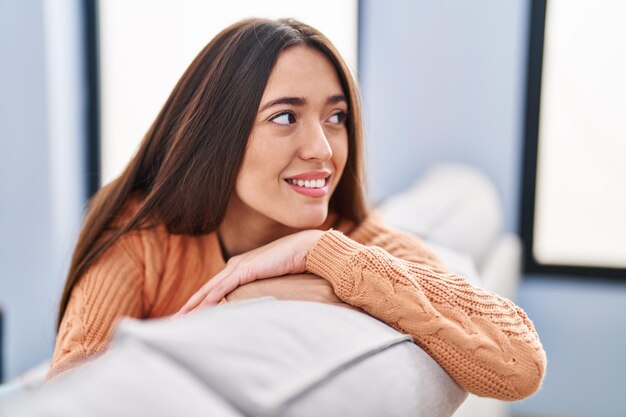 Young beautiful hispanic woman smiling confident sitting on sofa at home