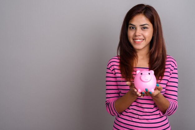 Young beautiful Indian woman against gray wall