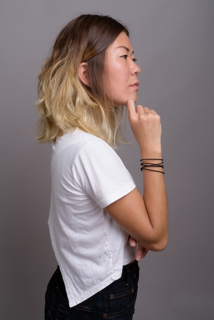 Young beautiful Kazakh woman against gray wall